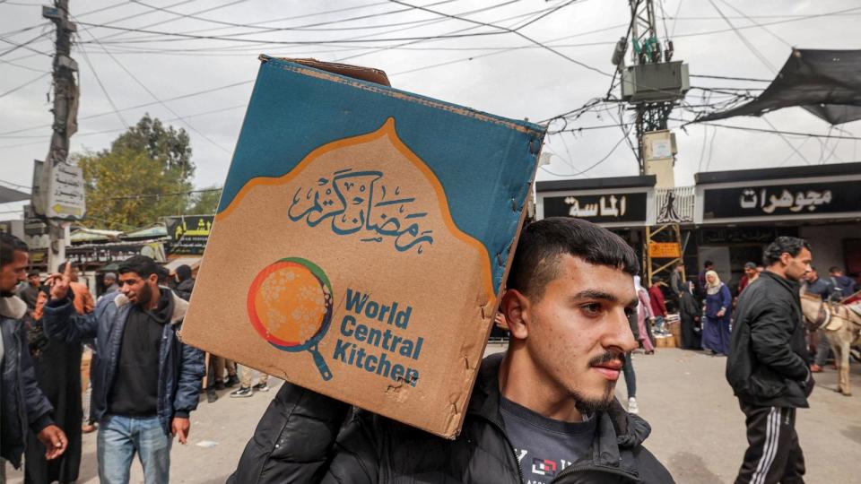 PHOTO: A man carries a cardboard box of food aid provided by non-profit non-governmental organization World Central Kitchen in Rafah in the southern Gaza Strip on March 17, 2024. (Mohammed Abed/AFP via Getty Images)