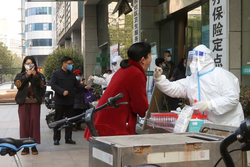 Un trabajador médico toma una muestra de hisopo en una cabina de prueba para la enfermedad por coronavirus, después de que el gobierno aflojó gradualmente las restricciones sobre el control de COVID-19, en Wuhan, provincia de Hubei, China