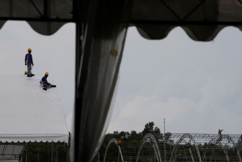 Workers construct outdoor building structures which will house an additional 1700 beds at Changi Exhibition Centre which has been repurposed into a community isolation facility, in Singapore