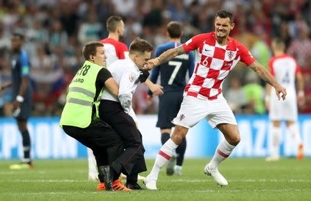 Soccer Football - World Cup - Final - France v Croatia - Luzhniki Stadium, Moscow, Russia - July 15, 2018 A steward apprehends a pitch invader while Croatia's Dejan Lovren looks on REUTERS/Carl Recine