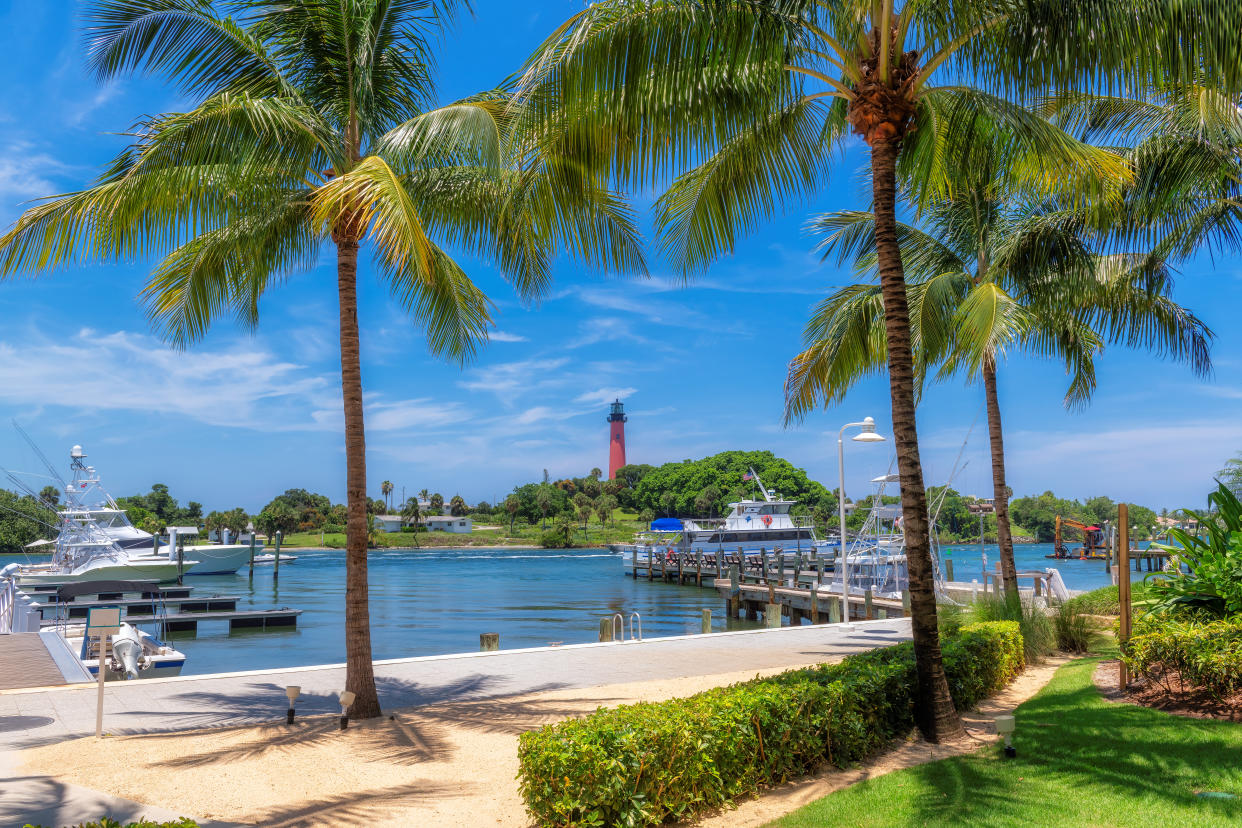 Jupiter lighthouse and harbor pictured with palm trees on a sunny summer day in West Palm Beach, FL