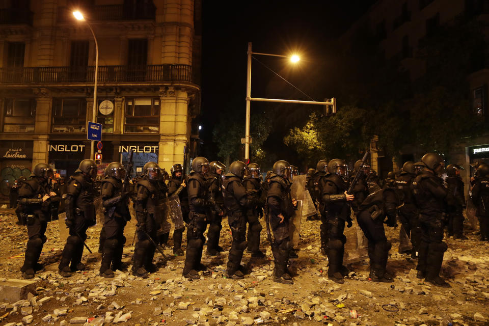 Police officers wait to advance on the fifth day of protests over the conviction of a dozen Catalan independence leaders in Barcelona, Spain, Friday, Oct. 18, 2019. Tens of thousands of flag-waving demonstrators demanding Catalonia's independence and the release from prison of their separatist leaders had earlier flooded downtown Barcelona. (AP Photo/Manu Fernandez)