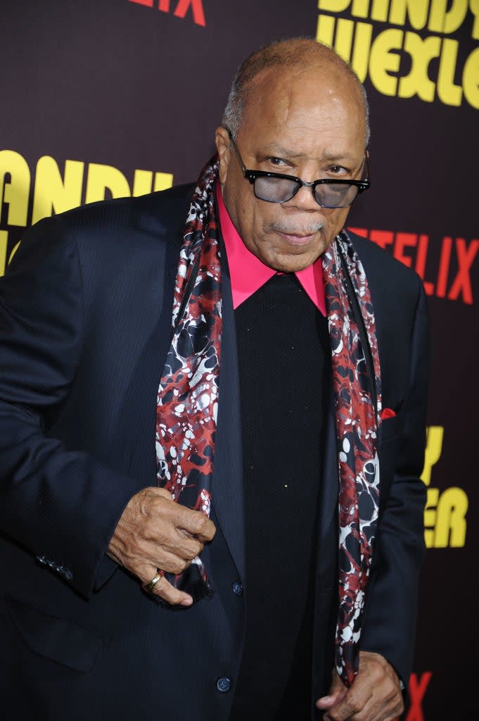 Quincy Jones on red carpet wearing a black suit with a patterned scarf