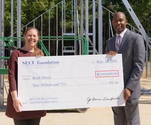 Liz Clasen-Kelly, Roof Above CEO (left), receives ceremonial check from Tyrone Tyler, SECU Regional Senior Vice President.