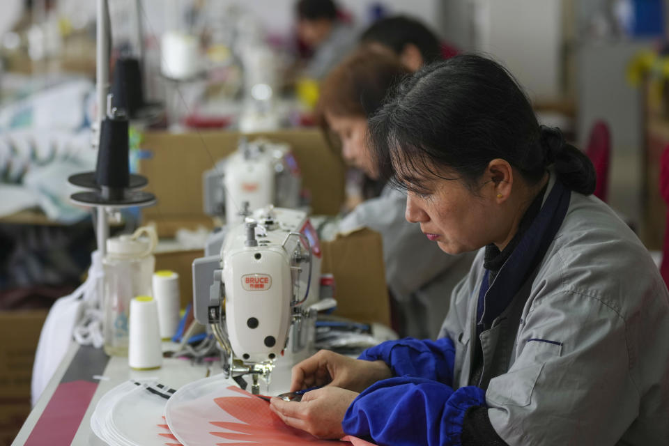 Workers stitch kites at a workshop in Weifang, Shandong Province of China, Friday, April 19, 2024. (AP Photo/Tatan Syuflana)