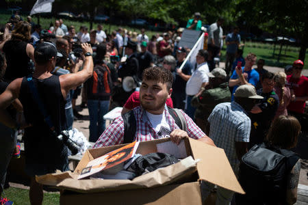 A man taking part in a anti-gun rally carries a box containing an image of a shooting victim out of a park after it was infiltrated by gun advocates carrying firearms on sidelines of the annual National Rifle Association (NRA) meeting in Dallas, Texas, U.S., May 5, 2018. REUTERS/Adrees Latif