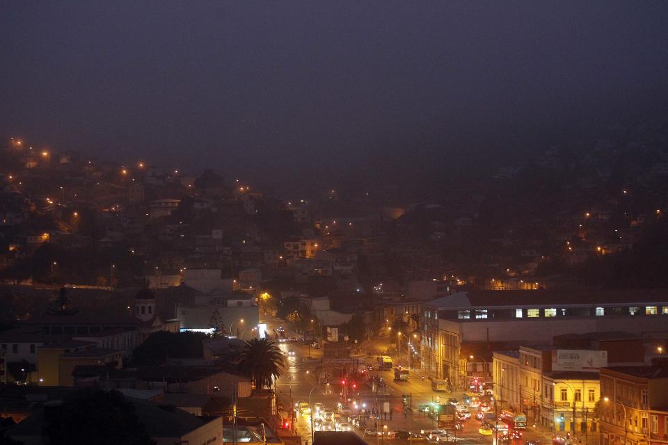 Niebla y humo se mezclan al amanecer en Valparaíso, Chile, el martes 15 de abril de 2014. Los grandes incendios que comenzaron el sábado pasado han dejado 15 muertos, más de 2.900 casas arrasadas y 12.500 damnificados. (Foto AP/Luis Hidalgo).