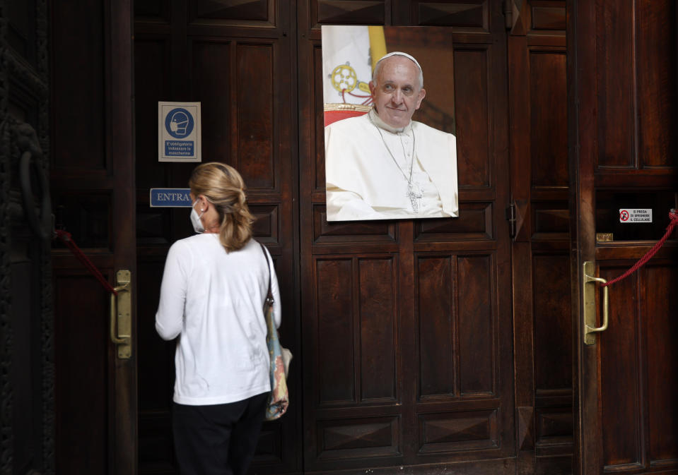 A woman passes past a portrait of Pope Francis as she enters the Argentine church of Santa Maria Addolorata (Our Lady of Sorrows) in Rome, Sunday, July 4, 2021. Pope Francis was hospitalized in Rome on Sunday afternoon for scheduled surgery on his large intestine, the Vatican said. The news came just three hours after Francis had cheerfully greeted the public in St. Peter’s Square and told them he will go to Hungary and Slovakia in September. (AP Photo/Riccardo De Luca)