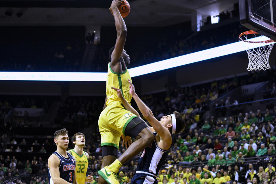 Oregon center N'Faly Dante dunks over Arizona guard Kerr Kriisa, right, during the first half of an NCAA college basketball game Saturday, Jan. 14, 2023, in Eugene, Ore. (AP Photo/Andy Nelson)