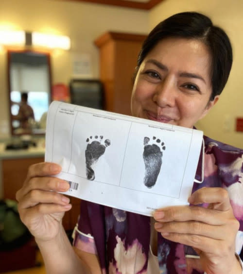 Alice with prints of her new baby's feet, believed to be born via surrogacy