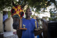 El entrenador de caballos Denis Hooker posa con su caballo Pereque y los trofeos ganadores de Pereque en la isla de San Andrés en Colombia, el viernes 11 de noviembre de 2022. (AP Foto/Iván Valencia)