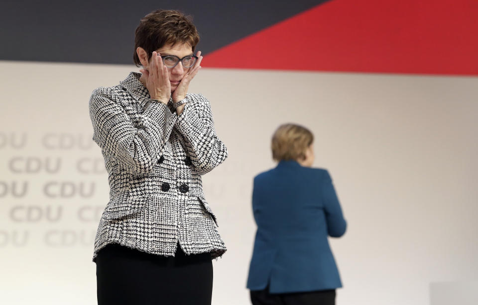 Newly elected CDU chairwoman Annegret Kramp-Karrenbauer, left, reacts during the party convention of the Christian Democratic Party CDU in Hamburg, Germany, Friday, Dec. 7, 2018, after German Chancellor Angela Merkel, right, didn't run again for party chairmanship after more than 18 years at the helm of the party. (AP Photo/Michael Sohn)