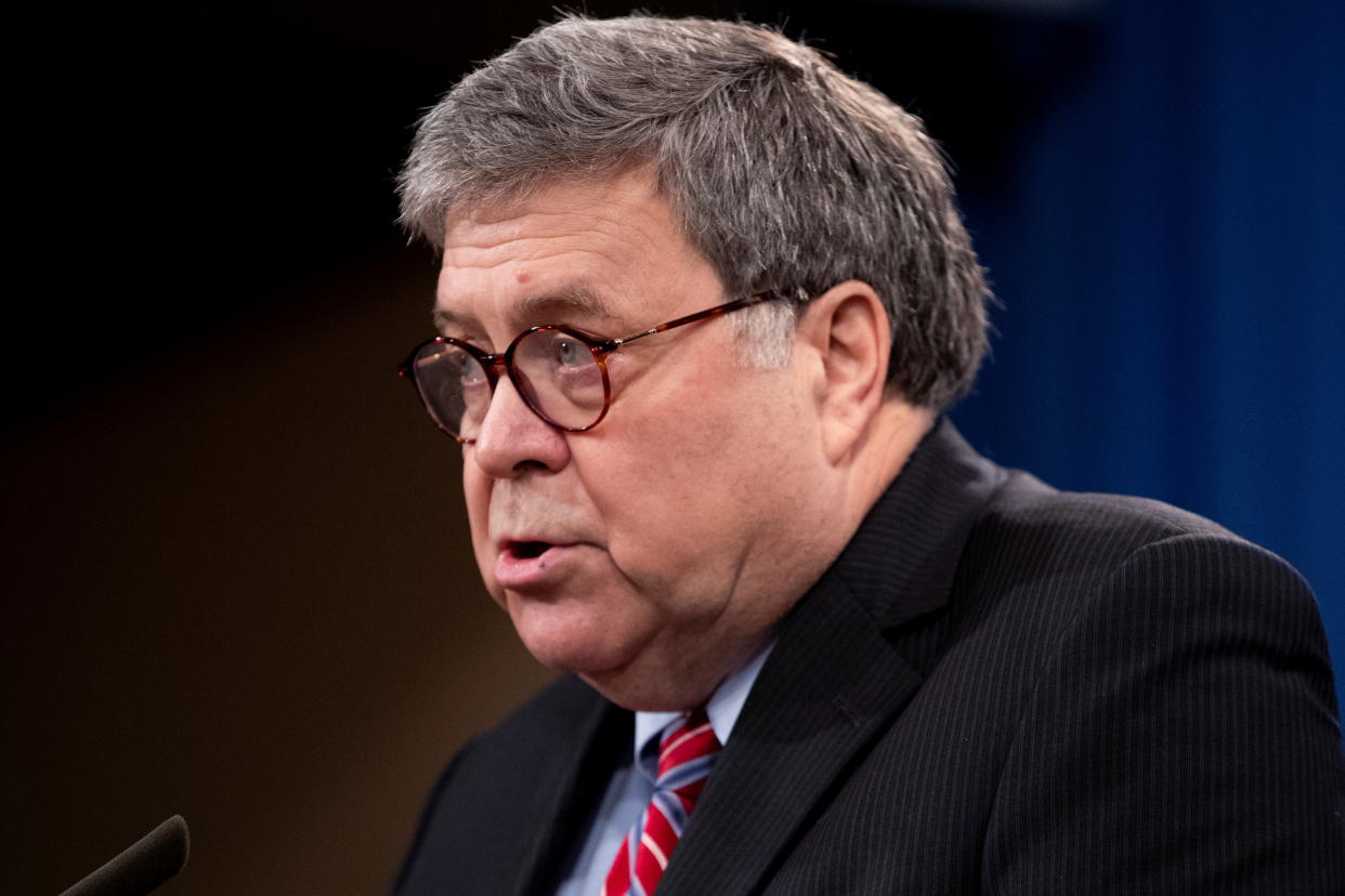William Barr speaks into a microphone.