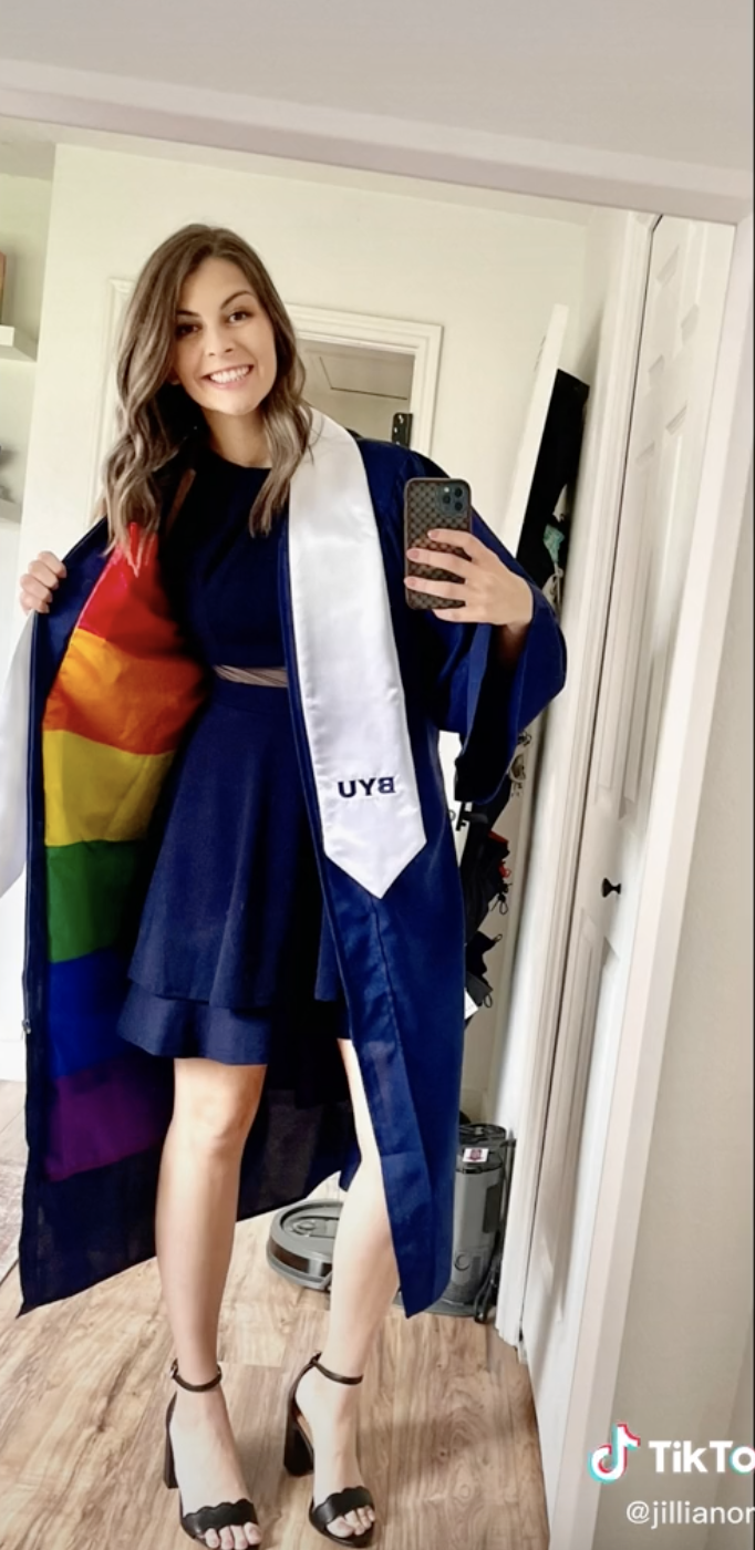 Jillian taking a selfie showing her Pride flag while wearing her BYU sash