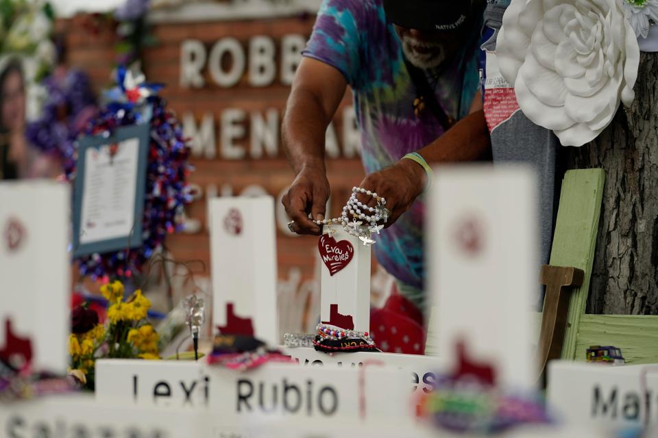 A visitor places bracelets on crosses at a memorial as he and others pay their respects to the victims killed at Robb Elementary School in Uvalde, Texas.