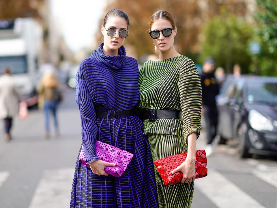 Twins wear blue and green striped dresses, a purple bag, and a red bag , outside Issey Miyake, during Paris Fashion Week Womenswear Spring/Summer 2018, on September 29, 2017 in Paris, France.