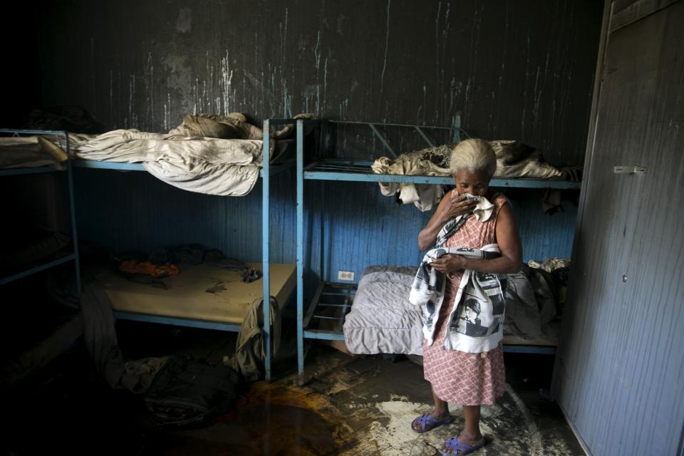 A staff worker of the Orphanage of the Church of Bible Understanding stands inside one of the bedrooms, the morning after a fire broke out at the facility in Kenscoff, on the outskirts of Port-au-Prince, Haiti, Friday, Feb. 14, 2020. A fire swept through this orphanage run by a Pennsylvania-based nonprofit group, killing over a dozen children, according to health care workers. (AP Photo/Dieu Nalio Chery)