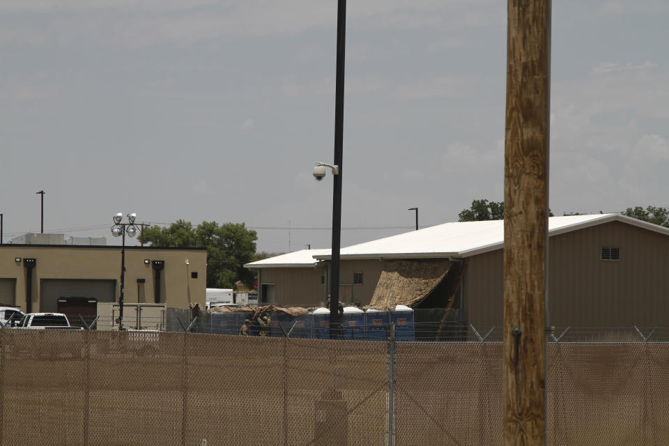 National Guard soldiers adjust a shade tarp over portable toilets adjacent to a building used for the detention of unaccompanied children in Border Patrol custody in Clint, Texas, Wednesday, June 26, 2019. Migrant children being housed at the Border Patrol facility near El Paso appeared mostly clean and were being watched by hallway monitors on Wednesday, less than a week since they reported living there in squalid conditions with inadequate food, water and sanitation. (AP Photo/Cedar Attanasio)