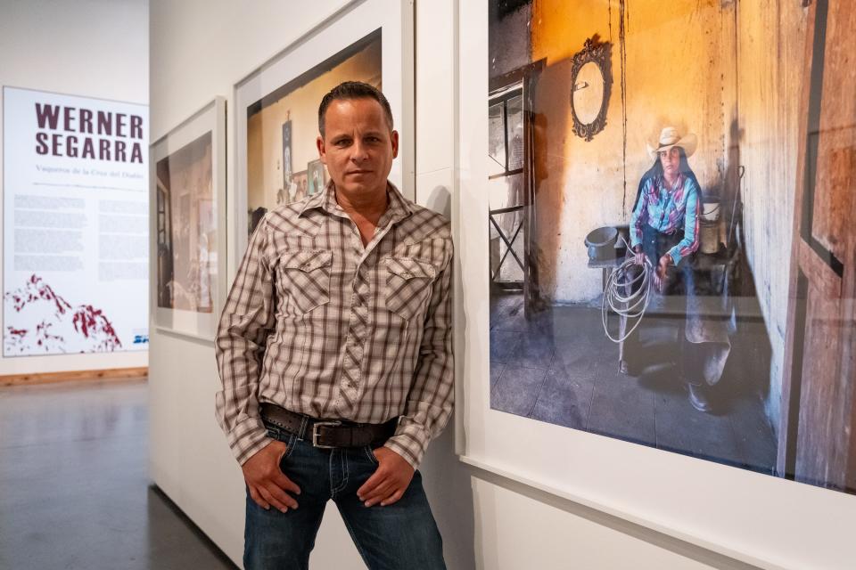 Werner Segarra poses for a portrait at his photography installation at Scottsdale's Museum of the West on July 21, 2023. He stands next to his photograph, titled, "Siri, Siria Guadalupe Duarte Anguiano. La Puerta del Arroyo Ranch."