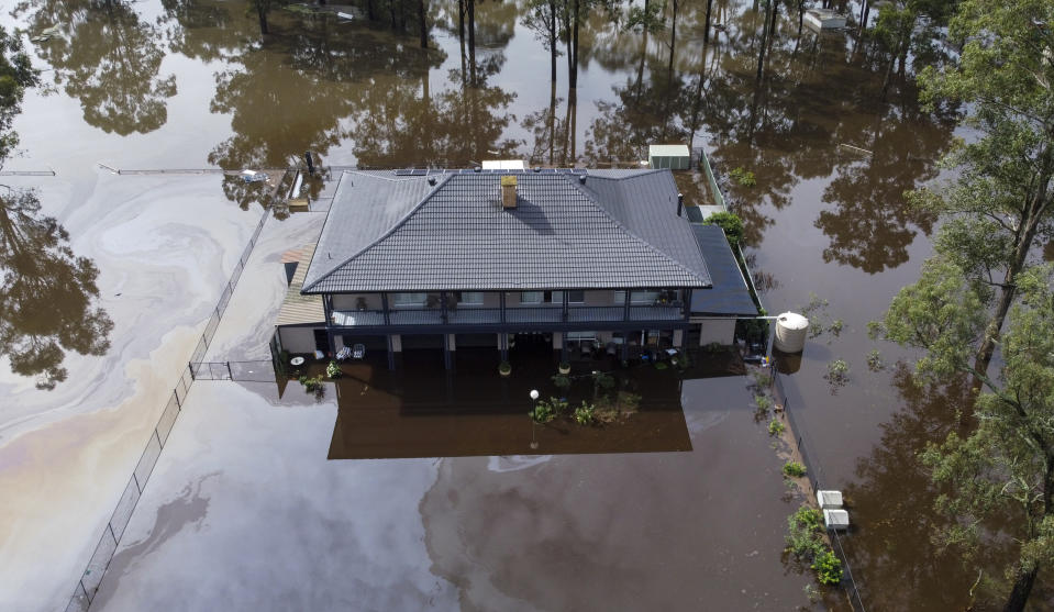 In this drone photo a house is surrounded by flood waters in Londonderry on the outskirts of Sydney, Australia, Tuesday, March 23, 2021. Hundreds of people have been rescued from floodwaters that have isolated dozens of towns in Australia's most populous state of New South Wales and forced thousands to evacuate their homes as record rain continues to inundate the countries east coast. (AP Photo/Mark Baker)