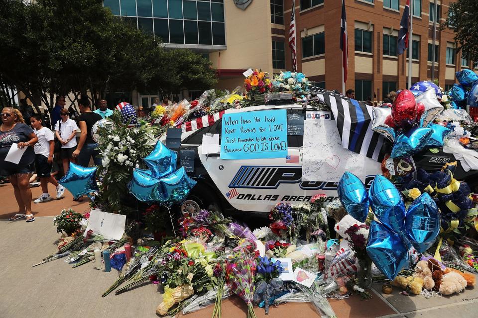 People visit a growing memorial at the Dallas police department's headquarters in downtown Dallas after the deaths of five police officers on July 9, 2016.