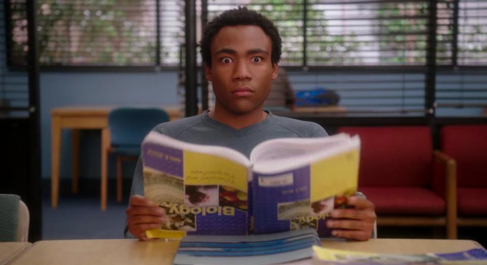 Troy holding a biology textbook upside down in "Community"