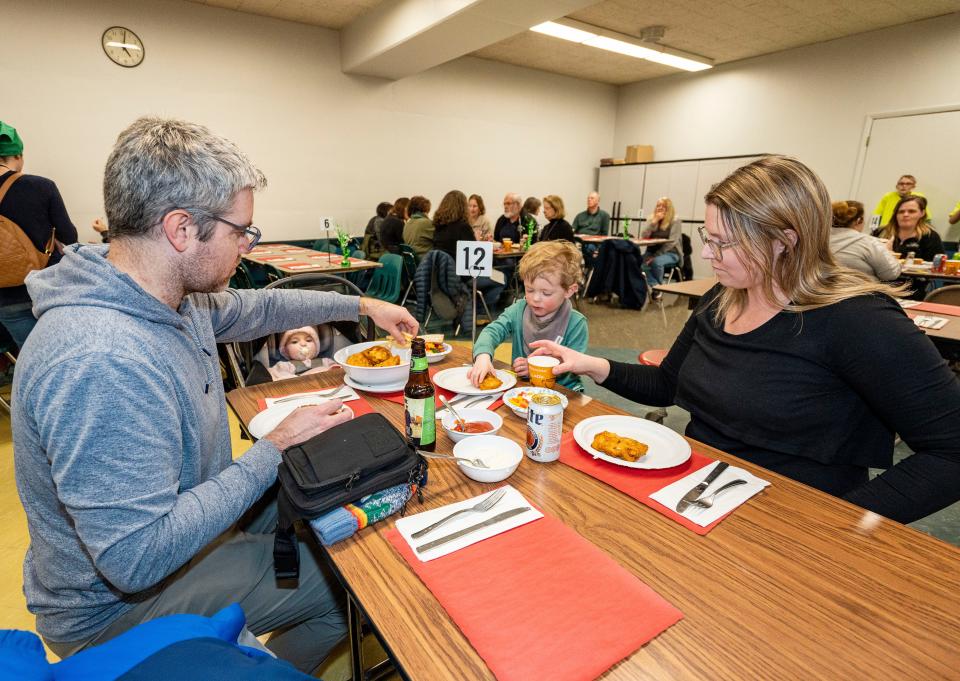 Bob and Lisa Manier eat dinner with their children, Archie, 2, and baby Judy, 6 months, during the St. Sebastian Parish fish fry. Ten years ago in Madison, Bob Manier kept a spreadsheet rating each of the fish fries he visited.