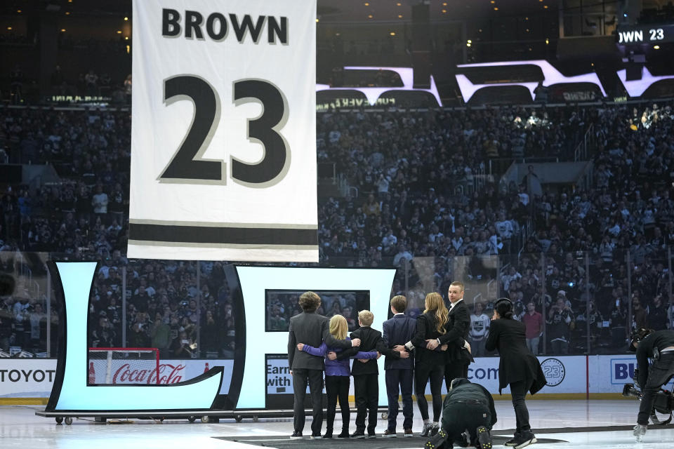 Former Los Angeles Kings right winger Dustin Brown turns around as he stands with his family while his number is lifted during a ceremony to retire his jersey prior to an NHL hockey game between the Los Angeles Kings and the Pittsburgh Penguins Saturday, Feb. 11, 2023, in Los Angeles. (AP Photo/Mark J. Terrill)
