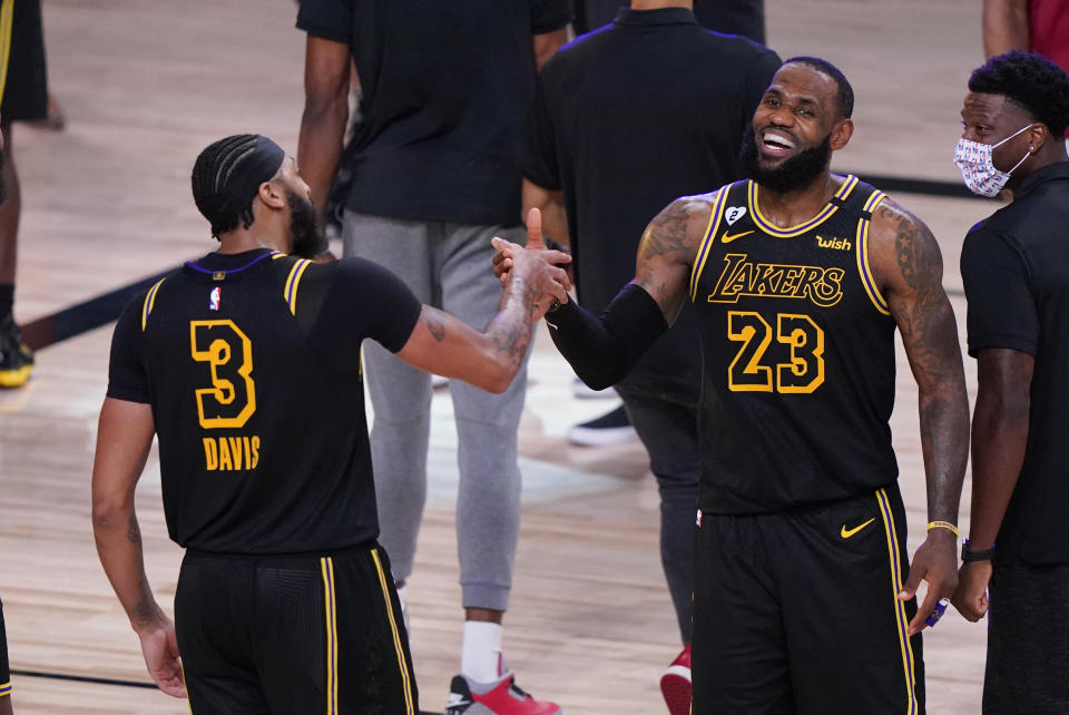 FILE - In this Sunday, Sept. 20, 2020, file photo, Los Angeles Lakers' LeBron James (23) celebrates with teammate Anthony Davis (3) after an NBA conference final playoff basketball game against the Denver Nuggets in Lake Buena Vista, Fla. The Lakers won 105-103. The jerseys will be hanging in their lockers when the Los Angeles Lakers arrive for Game 2 of the NBA Finals on Friday night, Oct. 2. Black jerseys, trimmed in gold, a snakeskin print on the exterior to make it further unique. They are the Black Mamba jerseys. Designed by Kobe Bryant — and now worn for Kobe Bryant. “We never want to lose in these jerseys,” Lakers forward Anthony Davis said. (AP Photo/Mark J. Terrill, File)