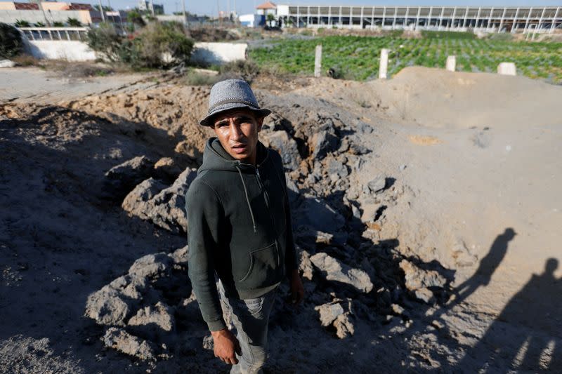 Palestinian man stands at the site of an Israeli air strike carried out in Gaza