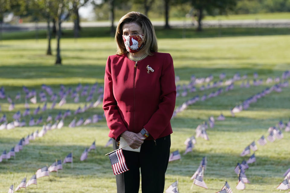 House Speaker Nancy Pelosi pauses and looks at small flags placed on the grounds of the National Mall by activists from the COVID Memorial Project to mark the deaths of 200,000 lives lost in the U.S. to COVID-19, Tuesday, Sept. 22, 2020 in Washington. (AP Photo/J. Scott Applewhite)