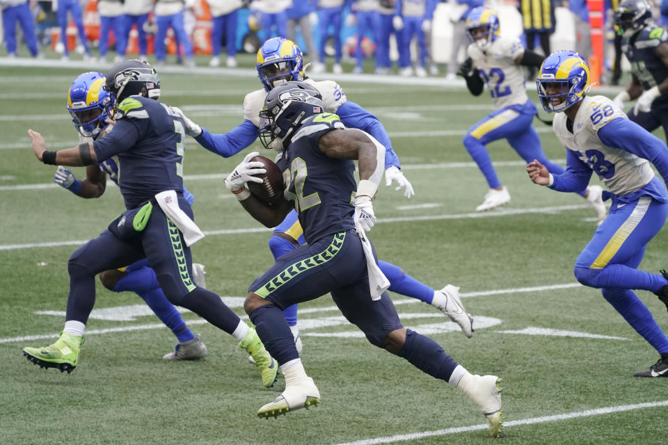 Seattle Seahawks quarterback Russell Wilson, second from left, blocks for running back Chris Carson on a carry by Carson against the Los Angeles Rams during the first half of an NFL wild-card playoff football game, Saturday, Jan. 9, 2021, in Seattle. (AP Photo/Ted S. Warren)