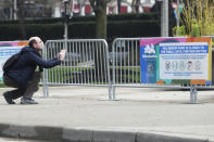 A man takes photos in front of a sign in downtown Chicago, Wednesday, April 22, 2020. Illinois Gov. Jay Pritzker said the state could reopen in stages, with each region facing different restrictions amid the COVID-19 pandemic.(AP Photo/Nam Y. Huh)