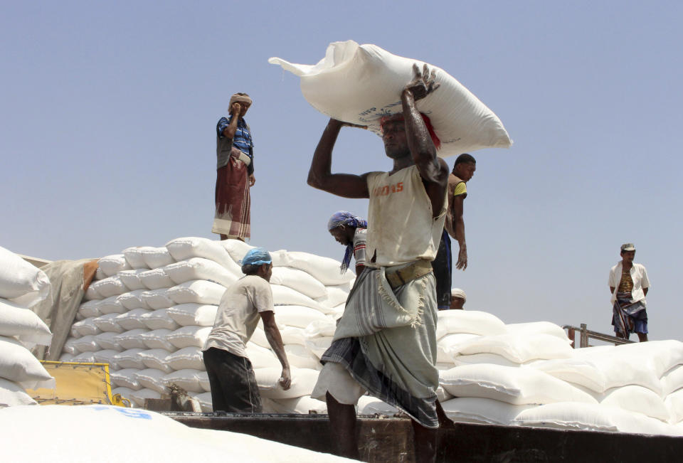 In this Sept. 21, 2018 photo, men deliver U.N. World Food Programme (WFP) aid in Aslam, Hajjah, Yemen. The United Nations and independent donors are rushing food to a desperate corner of northern Yemen where starving villagers were found to be living off leaves. But the hunger crisis continues to worsen. (AP Photo/Hammadi Issa)