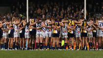 Crows and Eagles players link arms after the emotional match.