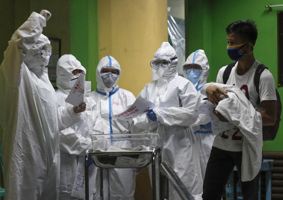 FILE - In this April 28, 2020, file photo, health workers wearing protective suits celebrate as 16-day-old baby Kobe Manjares who recovered from COVID-19 is received by his father, Ronnel, at the National Children's Hospital in Quezon city, Metro Manila, Philippines on Tuesday, April 28, 2020. Manjares’ 16-day-old son Kobe was heralded as the country's youngest COVID-19 survivor. But the relief and joy proved didn't last. Three days later, Kobe died on June 4 from complications of Hirschsprung disease, a rare birth defect. (AP Photo/Aaron Favila, File)