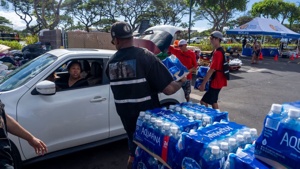 A woman collects water at a shopping center in Lahaina where different groups are handing out supplies. - Evelio Contreras/CNN