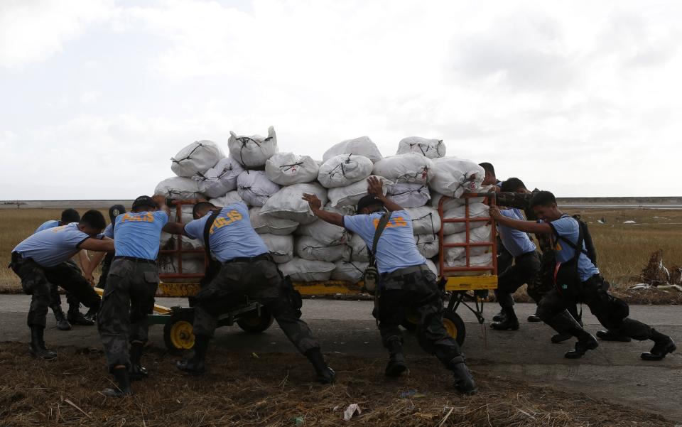 Police push a trolley containing relief supplies at Tacloban military base for the victims of super Typhoon Haiyan in Samar province