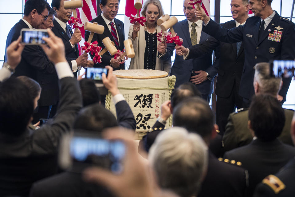 From left; Japan's Defense Minister Taro Kono, Foreign Minister Toshimitsu Motegi, deputy prime minister Taro Aso, Prime Minister Shinzo Abe, granddaughter Mary Jean Eisenhower and the great grandson Merrill Eisenhower Atwater of former U.S. President Dwight Eisenhower, acting U.S. Ambassador to Japan Joseph M. Young and Commander of the U.S. Forces in Japan Lieutenant General Kevin Schneider break a barrel of sake to celebrate the 60th anniversary commemorative reception of the signing of the Japan-US security treaty at the Iikura Guesthouse in Tokyo on Sunday, Jan. 19, 2020. (Behrouz Mehri/Pool Photo via AP)