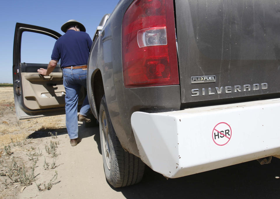 In this photo taken Tuesday, July 16, 2013, farmer Kole Upton climbs into his pickup which bears a sticker showing his opposition to the proposed high-speed rail system, at his ranch in Chowchilla, Calif. Upton is among many farmers in the Central Valley who say plans to build the $68 billion bullet train have led to years of uncertainty and financial burden. Upton says his family has put plans on hold to replace almond trees on the 1,400 acre farm as they await word on the final route. "They put a cloud on your land," Upton says.(AP Photo/Rich Pedroncelli)