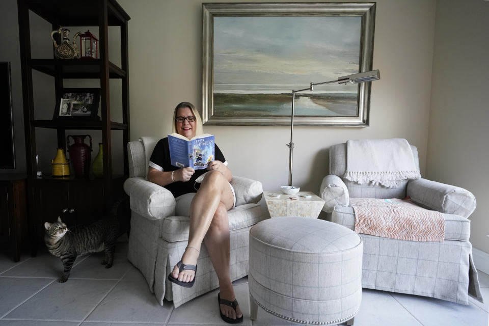 Kelly Vaiman poses for a photo in her living room where she sometimes likes to sit and read, Friday, Feb. 19, 2021, in Boynton Beach, Fla. Vaiman is an avid cozy mystery reader. (AP Photo/Wilfredo Lee)