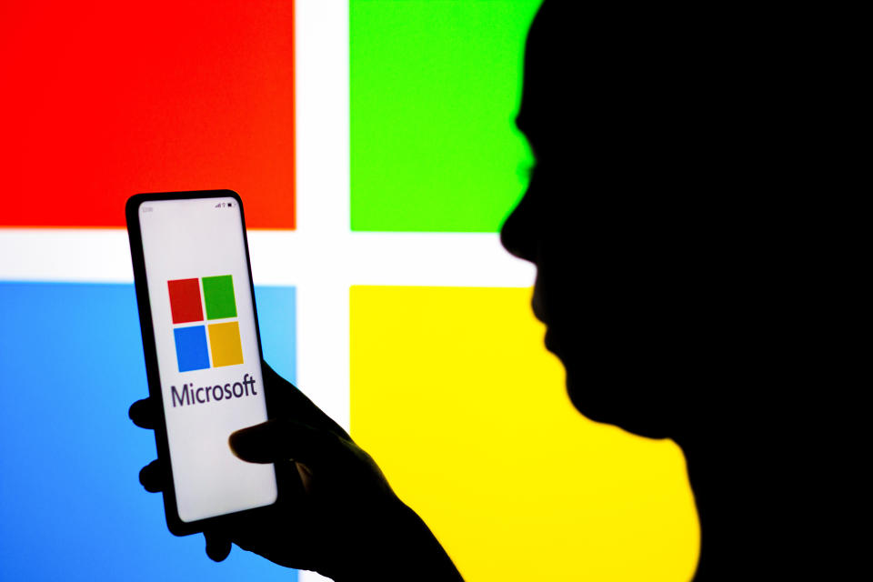 BRAZIL - 2022/03/21: In this photo illustration, a woman's silhouette holds a smartphone with the Microsoft Corporation logo displayed on the screen and in the background. (Photo Illustration by Rafael Henrique/SOPA Images/LightRocket via Getty Images)