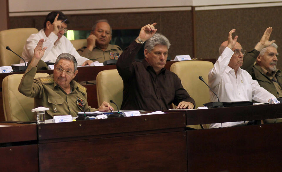 Cuba's Vice-President Miguel Diaz-Canel, center, Cuba's President Raul Castro, left, First Vice-President of the Council of State Jose Ramon Machado Ventura, second from right, and Commander of the Cuban Revolution Ramiro Valdes, right, raise their hands to vote the foreign investment law during an extraordinary session at the National Assembly in Havana, Cuba, Saturday, March. 29, 2014. Cuban lawmakers approved a law Saturday that aims to make it more attractive for foreign investors to do business in and with the country, a measure seen as vital if the island's struggling economy is to improve. IN the back row, also voting, Foreign Minster Bruno Rodrigues, left, and Defense Minister Leopoldo Cintas Frias, right. (AP Photo/Ismael Francisco, Cubadebate)