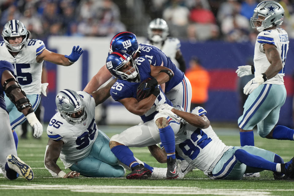 New York Giants' Saquon Barkley, center, is brought down by Dallas Cowboys defense during the first half of an NFL football game, Sunday, Sept. 10, 2023, in East Rutherford, N.J. (AP Photo/Bryan Woolston)