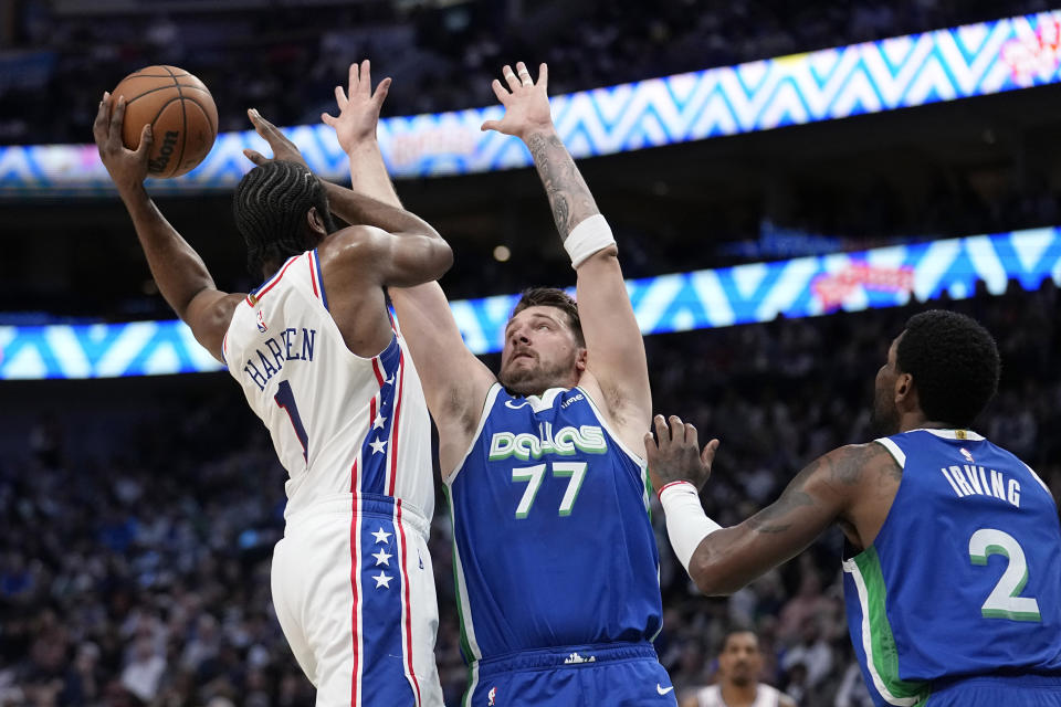 Philadelphia 76ers' James Harden (1) is forced to pass the ball as Dallas Mavericks' Luka Doncic (77) and Kyrie Irving (2) defend beneath the basket in the first half of an NBA basketball game, Thursday, March 2, 2023, in Dallas. (AP Photo/Tony Gutierrez)