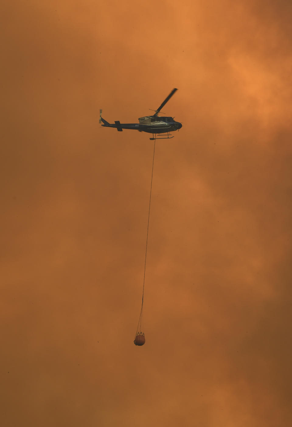 A helicopter drops water on a homestead as bushfires impact on farmland near the small town of Nana Glen, some 600kms north of Sydney on November 12, 2019. - Bushfires reached within kilometres (miles) of Sydney's city centre prompting firefighting planes to spray red retardant over trees and houses in a northern suburb. (Photo by WILLIAM WEST / AFP) (Photo by WILLIAM WEST/AFP via Getty Images)