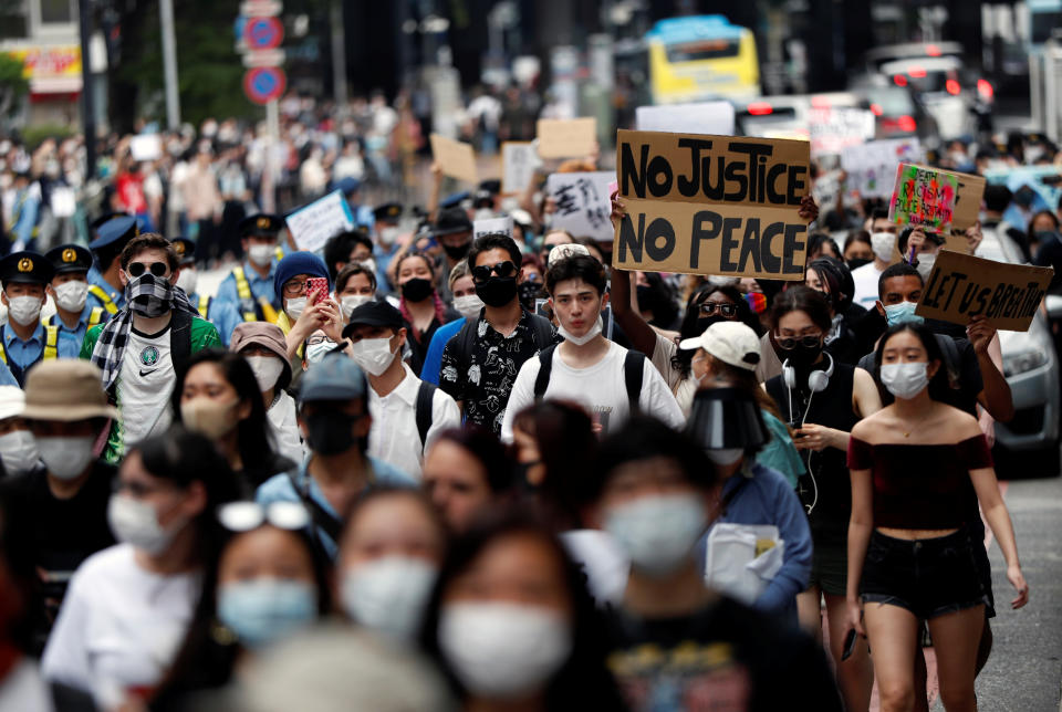 People wearing masks hold placards during a protest march over the alleged police abuse of a Turkish man, in echoes of a Black Lives Matter protest, following the death of George Floyd who died in police custody in Minneapolis, in Tokyo, Japan June 6, 2020.   REUTERS/Issei Kato