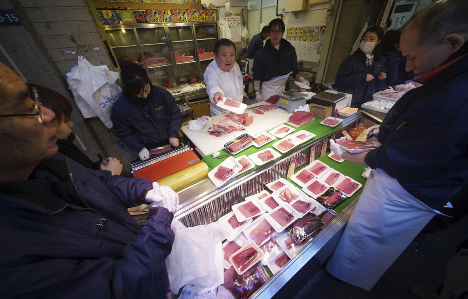 Kiyoshi Kimura (en el centro con camisa blanca), propietario de la cadena de restaurantes japoneses de sushi Sushi Zanmai, vende piezas de atún en una tienda junto al mercado de Tsukiji el pasado 29 de diciembre. (AP Photo/Eugene Hoshiko)