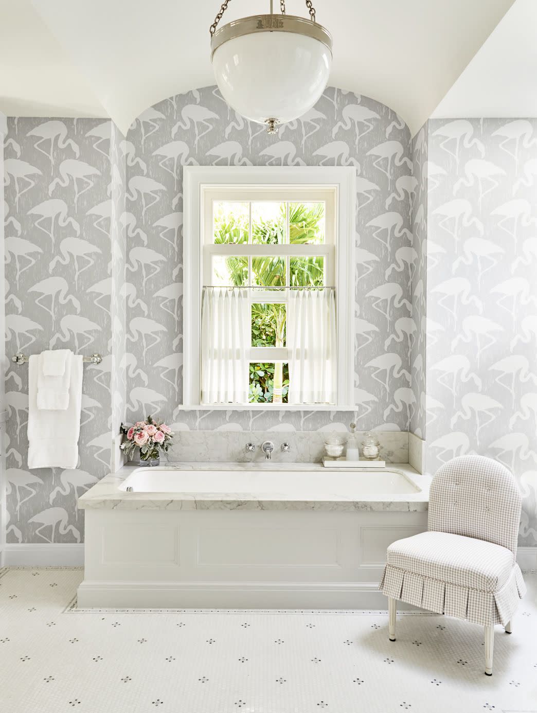 fun flamingo wallpaper in subtle gray and white on the walls around a soaking tub in a white bathroom