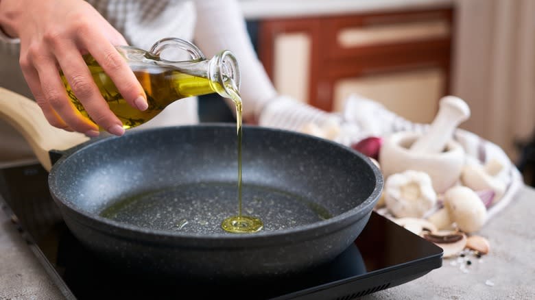 Woman pouring olive oil on frying pan